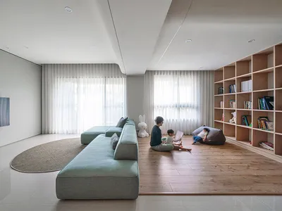 A modern minimalist living room with neutral-colored furniture and a large bookshelf.
