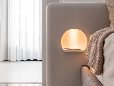 A minimalist bedroom with a soft, ambient light from a circular wall lamp made of light-colored wood.