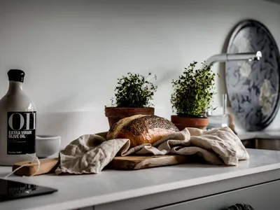 A modern kitchen with a wooden countertop, bread loaf, and potted plants on the counter.