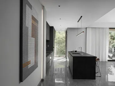 A modern minimalist kitchen with a black island and concrete countertop.