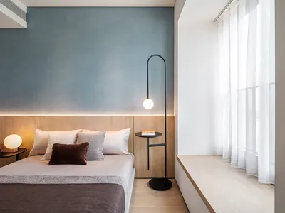 A modern minimalist bedroom with wooden furniture and a glass lamp on the side table.