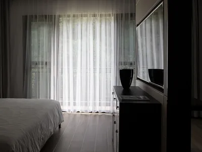 A modern bedroom with a bed, curtains, and a window.