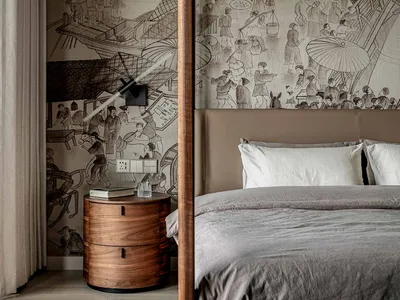 A modern bedroom featuring a four-poster bed with a brown headboard, gray bedding, and a wooden bedside table with a lamp and