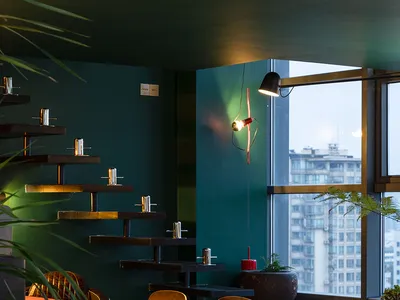 Industrial-style restaurant interior with wooden tables, metal chairs, and glass decor.