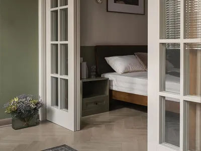 Modern bedroom with a white bed frame, green walls, and a wooden floor.