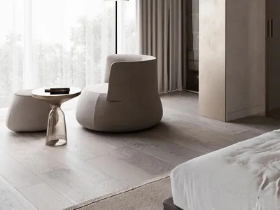 A modern minimalist bedroom with a white bed, beige armchair, and a white floor lamp.