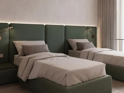 A modern minimalist bedroom with twin beds upholstered in green fabric, white bedding, and wall-mounted lamps.
