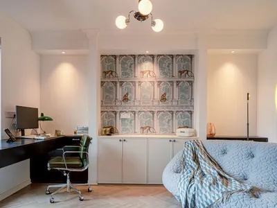 A modern home office space with a desk, computer, and quilted sofa.