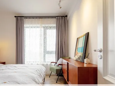 A minimalist bedroom with a bed, chair, and sideboard.