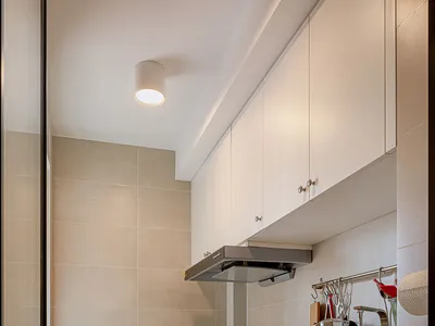Modern minimalist kitchen with black cabinets, white countertops, and concrete flooring.
