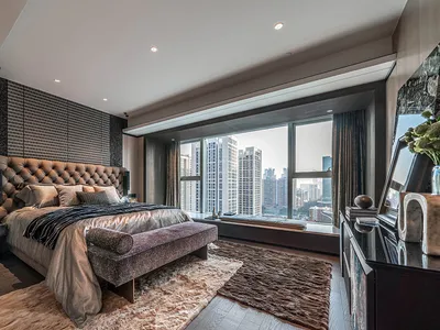 Modern bedroom with fabric headboard, glass windows, metal accents, and wooden flooring.