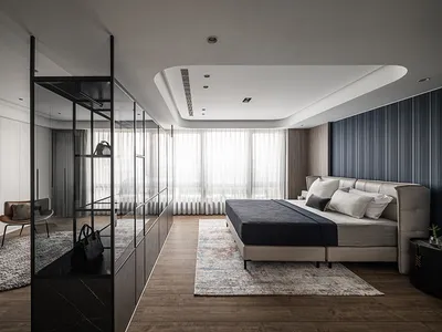 Modern minimalist bedroom with wooden floor, upholstered bed, and glass partition.