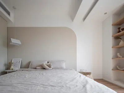 Minimalist bedroom with a grey fabric bed, wooden flooring, and white walls.
