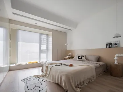 Minimalist bedroom featuring a wooden floor, a bed with a blanket, and a window with shutters.
