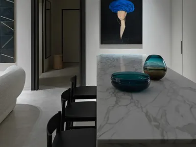 A modern, minimalist kitchen interior featuring a marble counter top with two glass bowls.