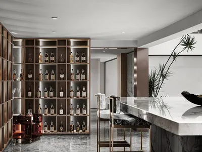 A modern bar with wooden shelves filled with bottles, a marble countertop, and concrete accents.