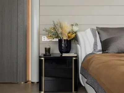 Modern bedroom interior featuring furniture made of wood and metal, adorned with dried flowers in a black vase, and a comfort