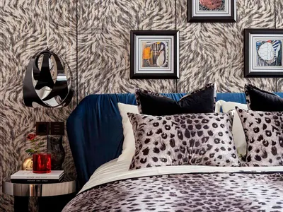Modern bedroom with leopard print bedding, blue headboard, and abstract artwork hanging on the wall.