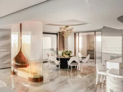 A modern living room featuring marble flooring and a kitchen area with a glass fireplace.