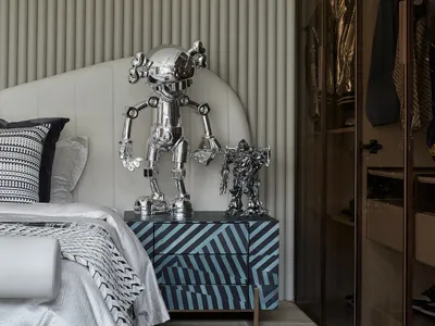 A modern monochrome bedroom featuring metallic sculptures on a patterned nightstand.