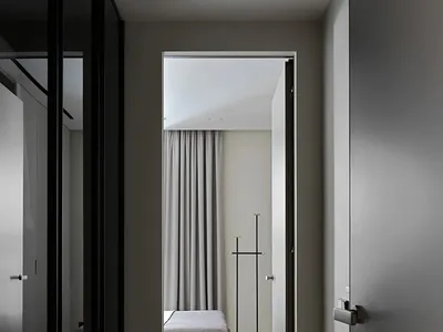 Minimalist bedroom with a grey upholstered bed, grey curtains, and wooden flooring.
