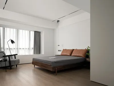 A minimalist bedroom featuring a wooden bed frame, leather headboard, and glass window with sheer curtains.