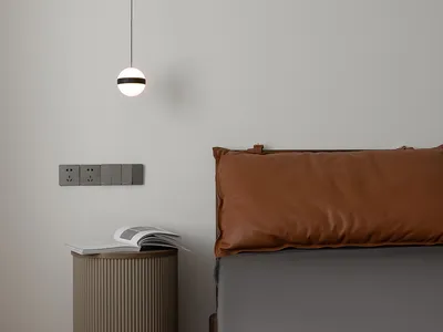 A modern bedroom featuring a brown leather cushion on a grey bed, photographed with a minimalist design style.