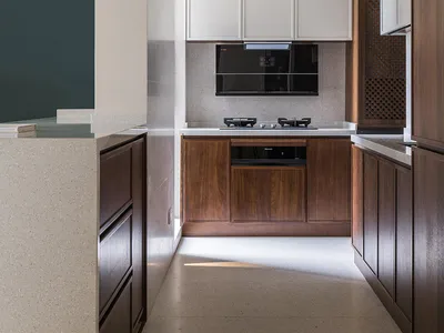 Modern kitchen interior with white cabinets, wooden accents, and marble countertops.