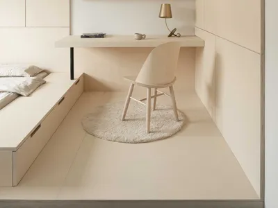 A minimalist bedroom with a wooden chair, desk, and wooden shelves.