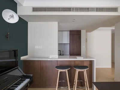 Modern kitchen featuring wood and white cabinets, white countertops, and black stools.