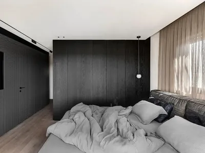 A contemporary bedroom featuring dark wooden walls and a messy bed.