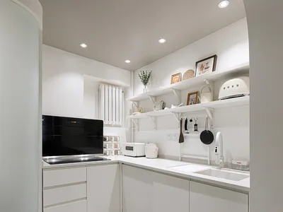 Modern kitchen with white cabinets, countertops, and appliances in a minimalist design.