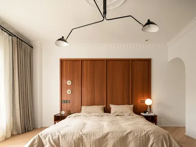 A minimalist bedroom with a wooden headboard and beige bedding.