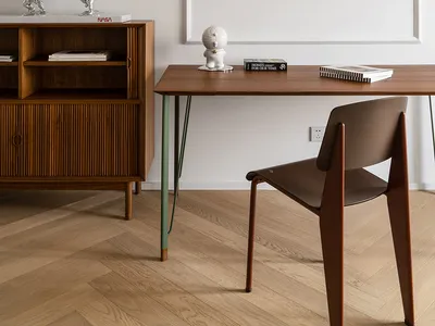 Minimalist home office featuring a wooden desk and chair against a white wall, with decorative items and lighting.