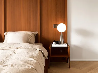 A modern minimalist bedroom featuring a wooden headboard and floor-to-ceiling wooden paneling.
