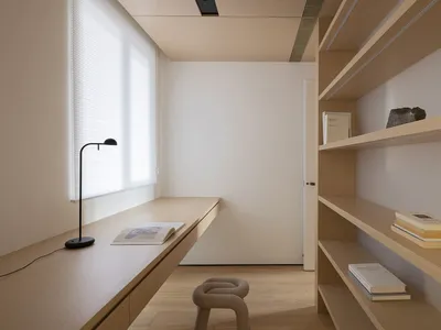 簡約風格的居家辦公室，配有木質書桌與層架，架上擺放書籍並有一盞黑色檯燈。