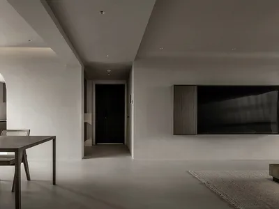 現代極簡客廳，鋪設混凝土地板，搭配深色木質家具，以及牆上懸掛的大型電視。