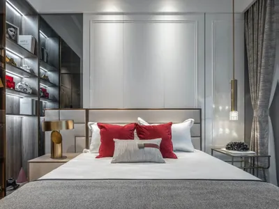 Modern bedroom featuring white and red fabric accents, with a prominent bed against a wall