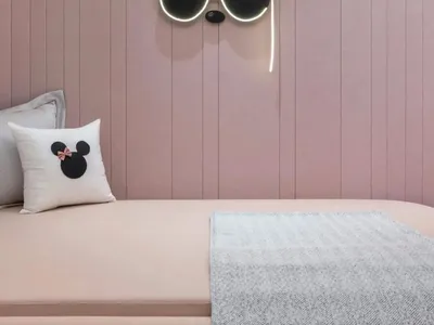 A minimalist bedroom with pink paneled walls and neon light