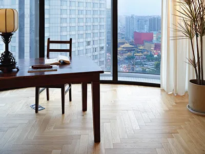 A modern home office with wooden furniture, glass windows, and a view of the city.