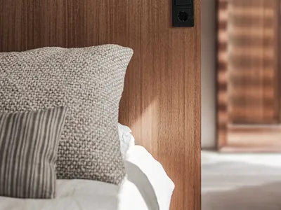 Modern, minimalist bedroom featuring a wooden headboard with a small bird sculpture on top.