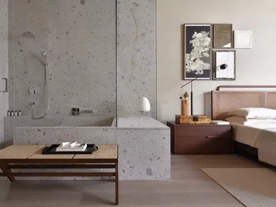 Modern bathroom with a concrete wall, a glass-enclosed shower, a floating nightstand, and a woven headboard bed.