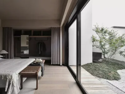 A modern minimalist bedroom featuring wooden flooring and furniture.