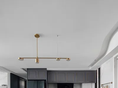 A modern kitchen featuring marble countertops and decorative lighting fixtures.