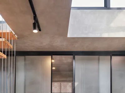 Modern minimalist bedroom featuring frosted glass walls and polished concrete ceiling and floor.