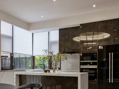 Contemporary kitchen featuring modern marble countertops and stainless steel appliances, with a black chair in the foreground