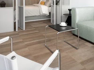 Modern minimalist bedroom with a glass-enclosed sleeping area, wooden flooring, and mint green sofa.