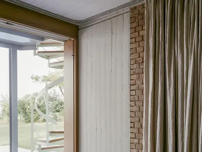 Minimalist bedroom featuring white curtains, wood paneling, and concrete elements.