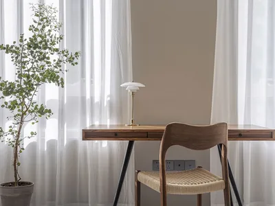 Modern minimalist home office with a wooden desk and white curtains.