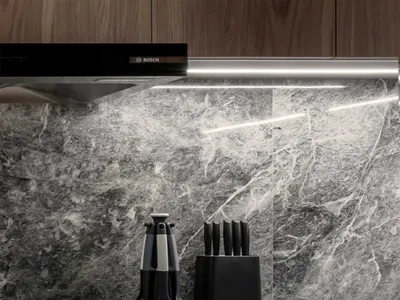 A modern kitchen featuring marble countertops and wooden cabinets.